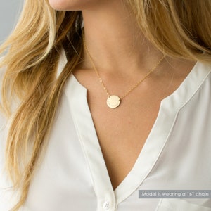 May include: Gold necklace with a round pendant that says "Live Your" on it. The model is wearing a 16 inch chain.