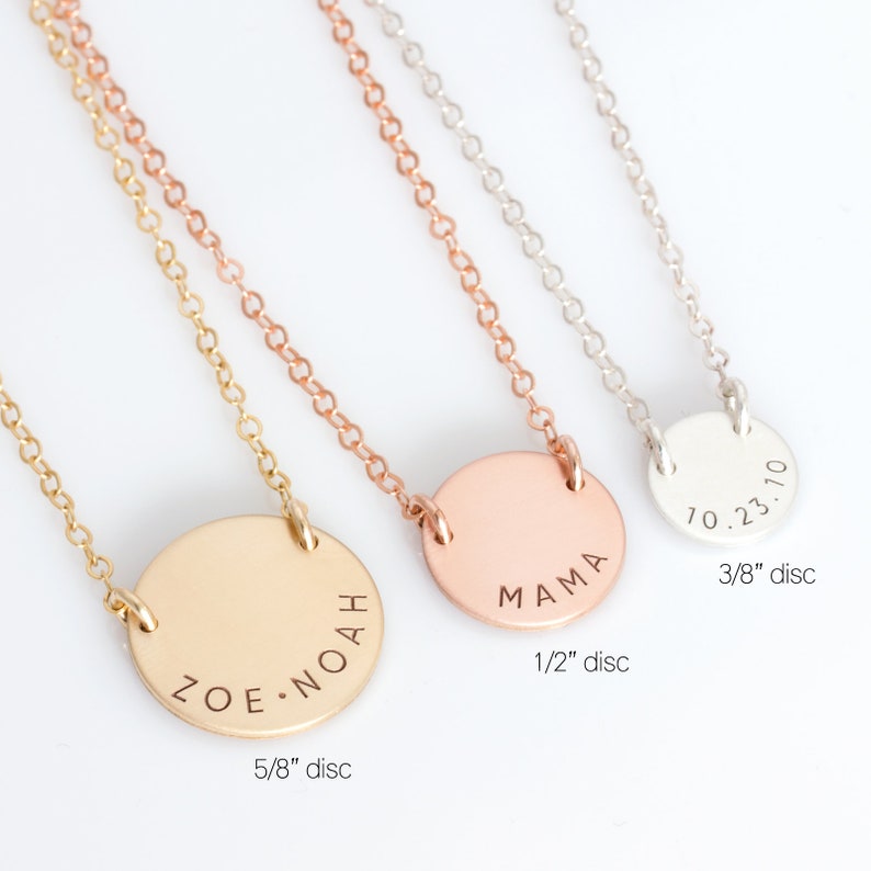 May include: Three gold necklaces with different sized round discs. The smallest disc is 3/8 inch and says "10.23.10". The middle disc is 1/2 inch and says "MAMA". The largest disc is 5/8 inch and says "ZOE.NOAH".