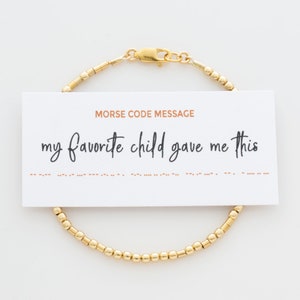 May include: Gold beaded bracelet with a clasp. The bracelet comes with a card that reads "Morse Code Message: my favourite child gave me this" and includes the message in Morse code.