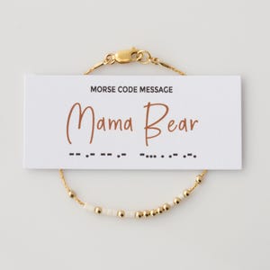 Peut inclure: Bracelet en perles dorées avec des perles blanches qui épellent "Mama Bear" en code Morse. Le bracelet est livré avec une carte qui montre la traduction en code Morse.
