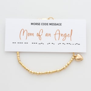 May include: Gold beaded bracelet with a heart charm. The bracelet comes with a card that reads "Morse Code Message Mom of an Angel" and shows the message in Morse code.
