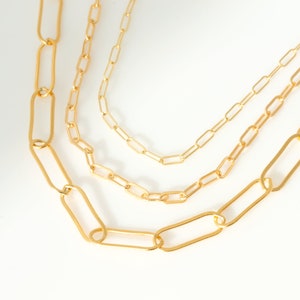 May include: Three gold chain necklaces with different sized links. The chains are layered on top of each other.