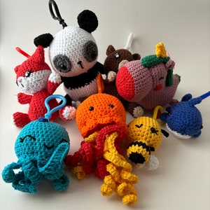 May include: A collection of crocheted stuffed toys, including a panda, a cat, a unicorn, a bee, an octopus, and a jellyfish. The toys are all brightly coloured and have cute faces.