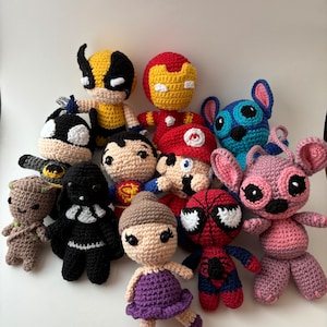Könnte beinhalten: Eine Sammlung von gehäkelten Plüschtieren mit verschiedenen Charakteren, darunter ein rot-gelber Iron Man, ein blauer Stitch, ein lila-braunes Mädchen, ein rot-blauer Spiderman, ein schwarz-weißer Darth Vader, ein brauner Groot, ein gelber Wolverine, ein rot-weißer Mario, ein blau-weißer Stitch und ein rosa-weißer Engel.