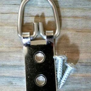 May include: A silver metal picture hanging hook with two screw holes and two screws. The hook has a D-ring shape.