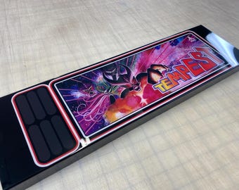 May include: Black control panel with a red and white border. The panel features a colorful image of a space scene with the word "TEMPEST" in large white letters.