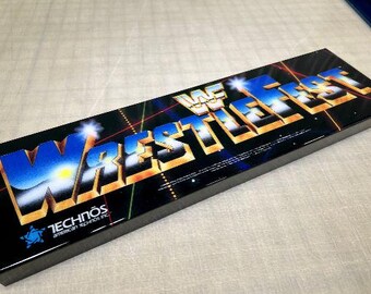 May include: A black arcade game cabinet with a gold and blue logo that reads "WWF Wrestlefest". The cabinet has a black background with a blue and yellow design. The text "Technos American Technos Inc." is printed in white on the cabinet.
