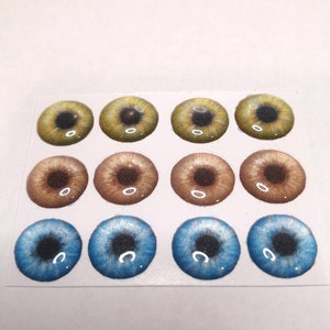 May include: A sheet of twelve self-adhesive plastic doll eyes. The eyes are in three colors: yellow, brown, and blue. Each eye has a black pupil and a white iris.
