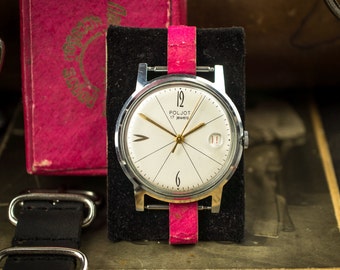 Könnte beinhalten: Eine Vintage-Poljot-Armbanduhr mit weißem Zifferblatt, goldenen Zeigern und Datumsfenster. Die Uhr hat ein silberfarbenes Gehäuse und ein pinkfarbenes Lederarmband. Auf dem Zifferblatt steht „POLJOT 17 jewels“.