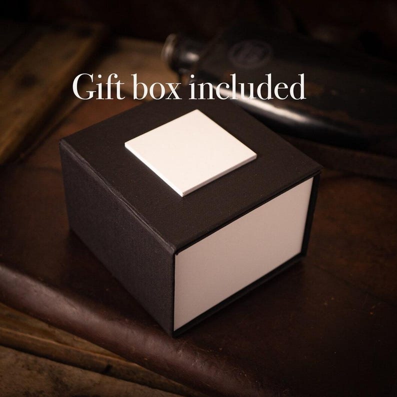 May include: A black gift box with a white lid. The box is sitting on a brown leather surface. The text "Gift box included" is visible in the image.