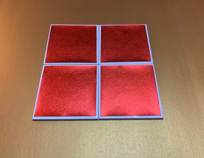 Peut inclure: Quatre sous-verres carr&eacute;s rouges avec une bordure blanche. Les sous-verres ont une surface textur&eacute;e.