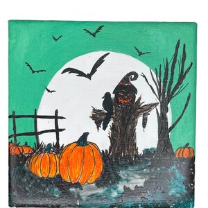 Op de afbeelding: Een Halloween-schilderij met een vogelverschrikker met een pompoengezicht, een zwarte kraai en oranje pompoenen. De achtergrond toont een volle maan, vleermuizen en een groene lucht. Een hek en een kale boom zijn ook zichtbaar.