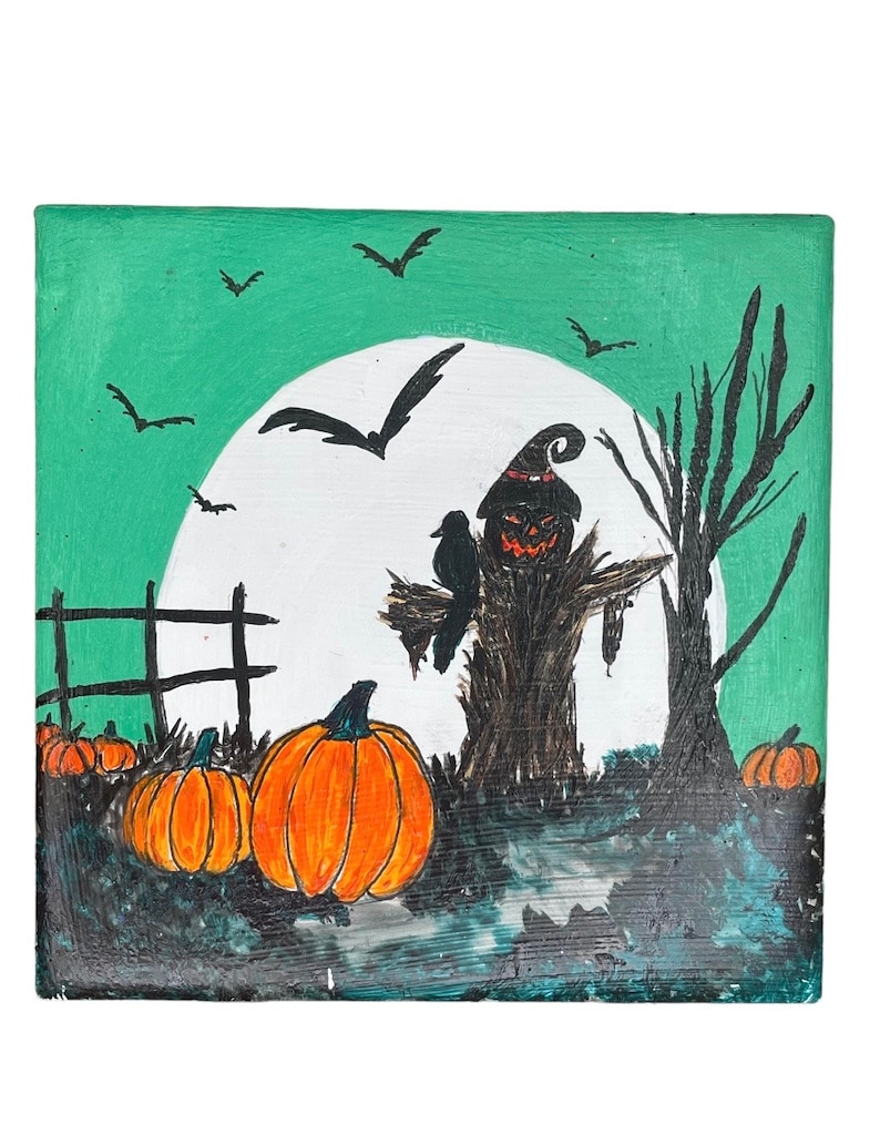 Op de afbeelding: Een Halloween-schilderij met een vogelverschrikker met een pompoengezicht, een zwarte kraai en oranje pompoenen. De achtergrond toont een volle maan, vleermuizen en een groene lucht. Een hek en een kale boom zijn ook zichtbaar.