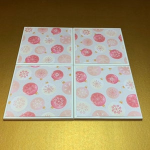 Peut inclure: Ensemble de quatre sous-verres en c&eacute;ramique blanche avec un motif d'ornements roses et dor&eacute;s.