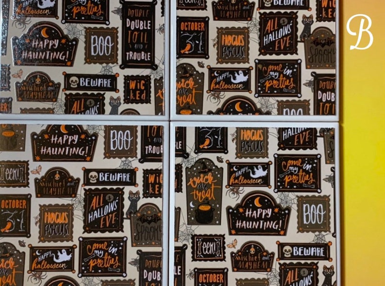 Pu&ograve; includere: Un set di quattro sottobicchieri quadrati con un motivo di Halloween ripetuto su sfondo chiaro. Il design include testi incorniciati in nero e arancione come Happy Haunting, Boo, Beware, Hocus Pocus e All Hallows Eve, insieme a illustrazioni di fantasmi, ragni, ragnatele e gatti.