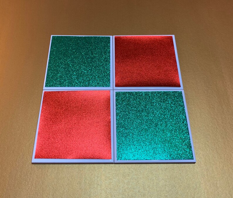 Peut inclure: Quatre sous-verres carr&eacute;s avec une finition paillet&eacute;e. Deux sous-verres sont rouges et deux sont verts.