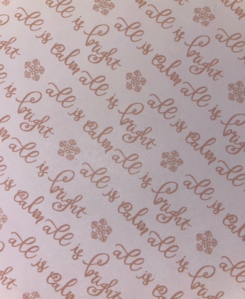 May include: A white background with a repeating pattern of the phrase "all is calm all is bright" in a cursive font. The phrase is printed in a light brown colour. Small snowflake designs are scattered throughout the background.