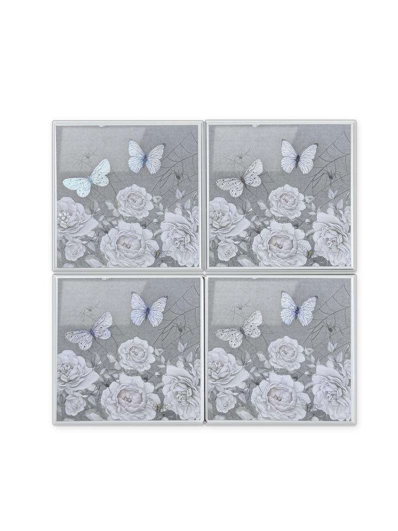 Peut inclure: Un ensemble de quatre dessous de verre carr&eacute;s pr&eacute;sentant un motif floral gris monochrome avec des roses blanches, des toiles d'araign&eacute;e d&eacute;licates et deux papillons sur chaque pi&egrave;ce. Les dessous de verre sont encadr&eacute;s de m&eacute;tal argent&eacute; fin.