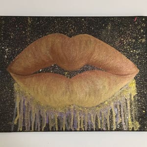 Pu&ograve; includere: Un primo piano di un dipinto di un paio di labbra con una finitura glitter dorata. Le labbra sono dipinte su uno sfondo nero con accenti di glitter dorati e viola.