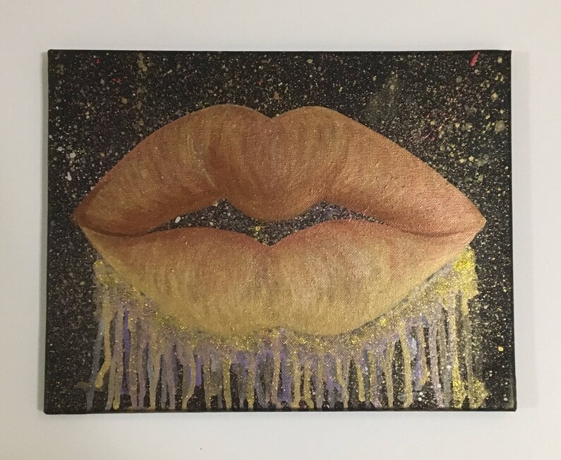 Pu&ograve; includere: Un primo piano di un dipinto di un paio di labbra con una finitura glitter dorata. Le labbra sono dipinte su uno sfondo nero con accenti di glitter dorati e viola.
