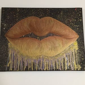 Pu&ograve; includere: Un primo piano di un dipinto di un paio di labbra con glitter dorati e viola che gocciolano dal fondo. Le labbra sono dipinte in tonalit&agrave; di marrone e arancio.