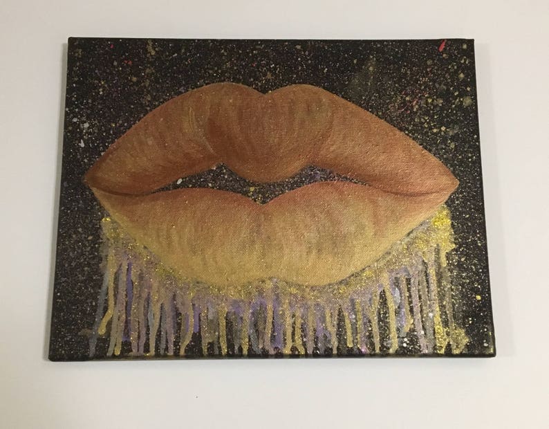Pu&ograve; includere: Un primo piano di un dipinto di un paio di labbra con glitter dorati e viola che gocciolano dal fondo. Le labbra sono dipinte in tonalit&agrave; di marrone e arancio.