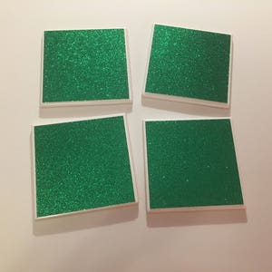 May include: Four square green glitter coasters with white borders.