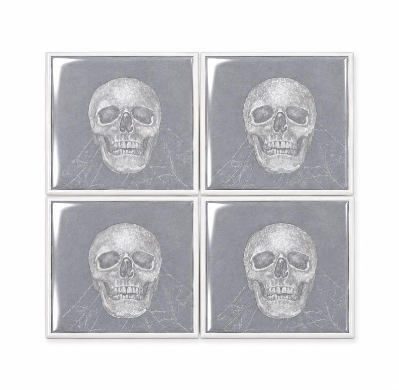 Peut inclure: Un ensemble de quatre dessous de verre carr&eacute;s, chacun pr&eacute;sentant une illustration au trait blanc d'un cr&acirc;ne humain centr&eacute;e sur un fond gris uni. Le motif du cr&acirc;ne est d&eacute;taill&eacute; avec des dents, des orbites et une cavit&eacute; nasale visibles.