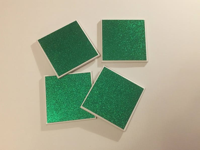 May include: Four square green glitter coasters with white borders.