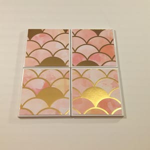 K&ouml;nnte beinhalten: Satz mit vier quadratischen Untersetzern mit einem rosa-goldenen Aquarelldesign. Das Design zeigt ein sich wiederholendes Muster aus &uuml;berlappenden Halbkreisen.
