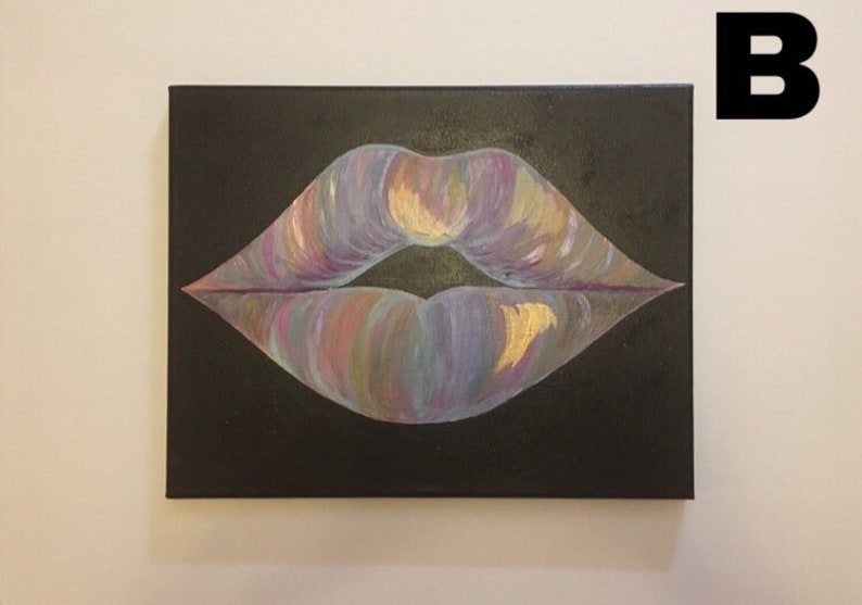 May include: A rectangular canvas painting featuring a pair of lips centered on a solid black background. The lips are rendered with blended strokes of iridescent purple, blue, pink, and gold paint, creating a shimmering, multi-colored effect.