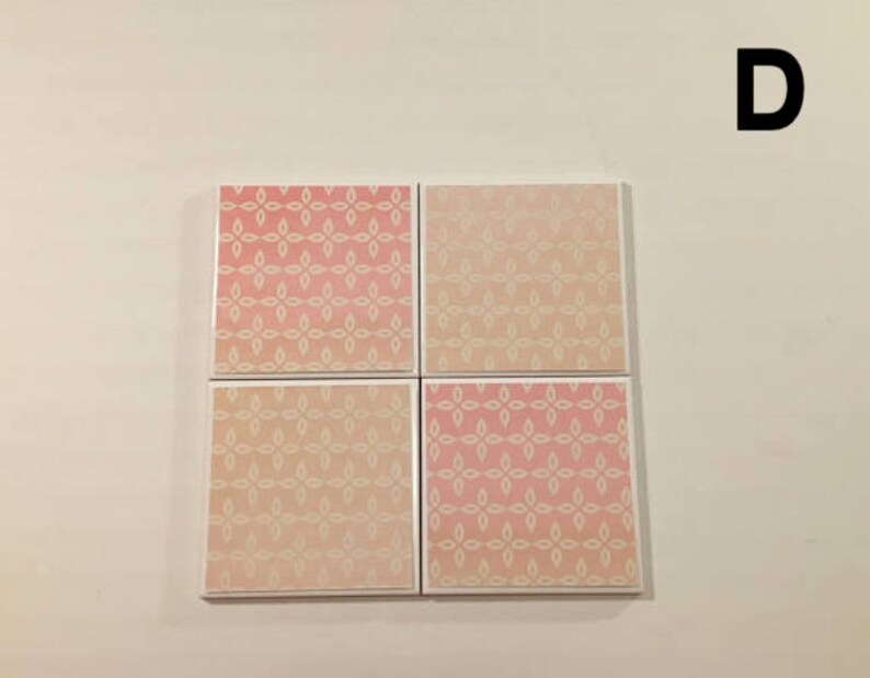 K&ouml;nnte beinhalten: Satz mit vier quadratischen Untersetzern mit einem geometrischen Muster in Rosa und Wei&szlig;. Die Untersetzer haben einen wei&szlig;en Rand.