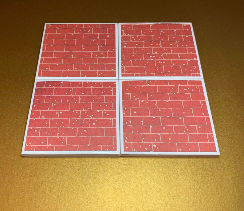 May include: Set of four red brick patterned coasters. The coasters are square and have a white border.