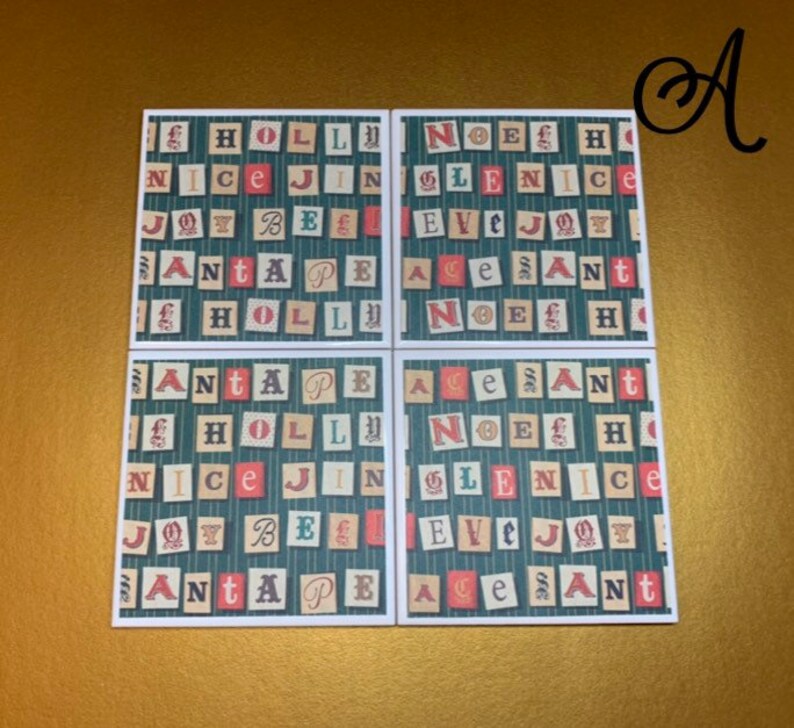 May include: Four square coasters with a Christmas theme. Each coaster features a green background with a white grid pattern. The coasters are decorated with red, white, and blue letters that spell out the words "HOLLY", "NICE", "JOY", "SANTA", "NOEL", "GLEN", "EVE", "ACE", and "SANT".