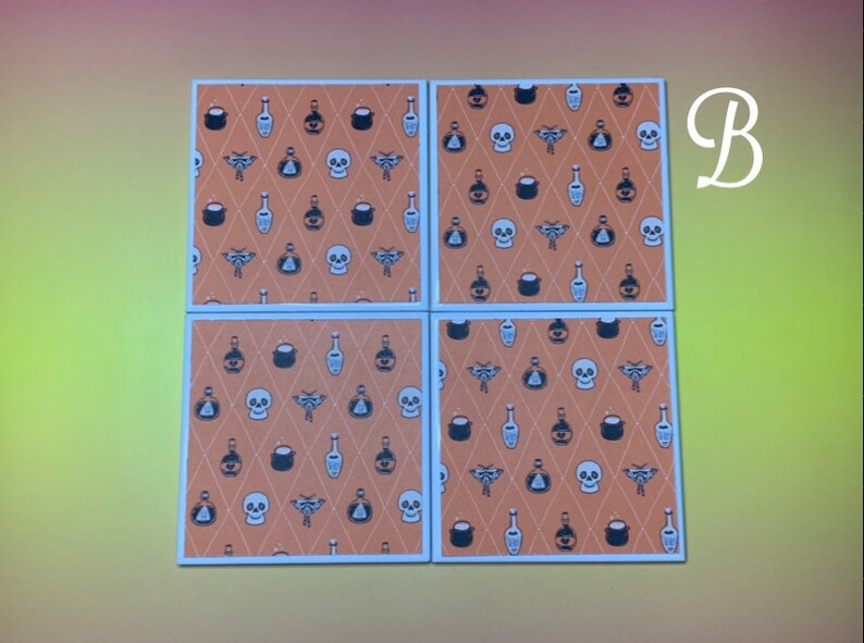 Puede incluir: Cuatro posavasos cuadrados con un patr&oacute;n repetido de calaveras, botellas de pociones y otros iconos tem&aacute;ticos de Halloween sobre un fondo de diamantes naranja. Los posavasos tienen bordes blancos.