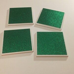 May include: Four square green glitter coasters with white borders.