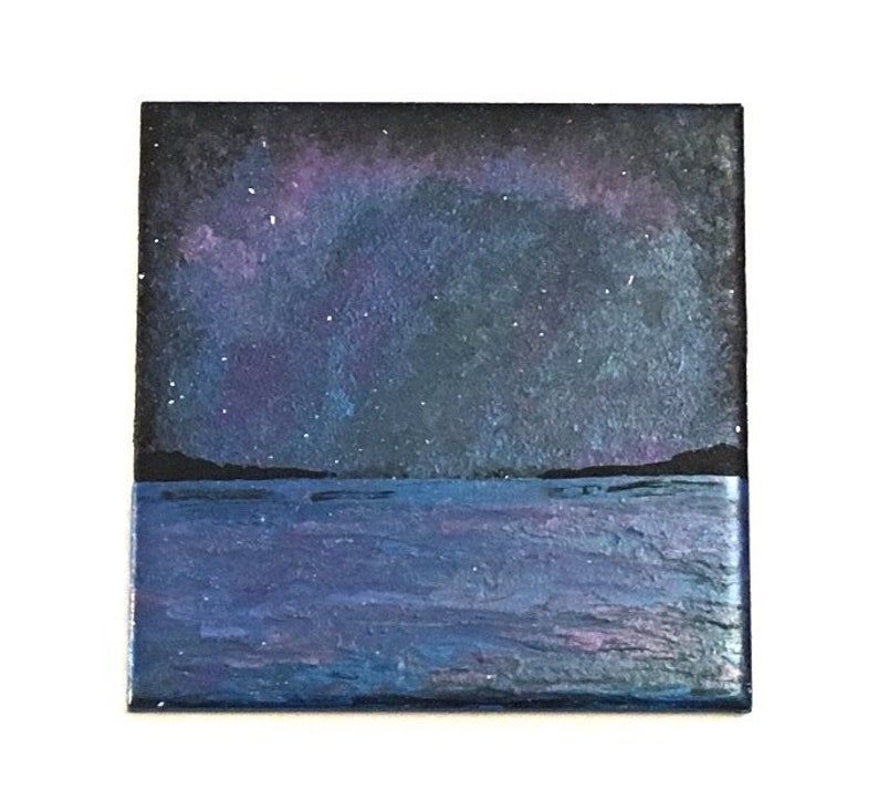Puede incluir: Una pintura de un cielo nocturno estrellado sobre un cuerpo de agua azul oscuro. El cielo es de un azul profundo con un efecto de aurora boreal p&uacute;rpura y rosa. El agua es de un azul oscuro con un ligero efecto de ondulaci&oacute;n.