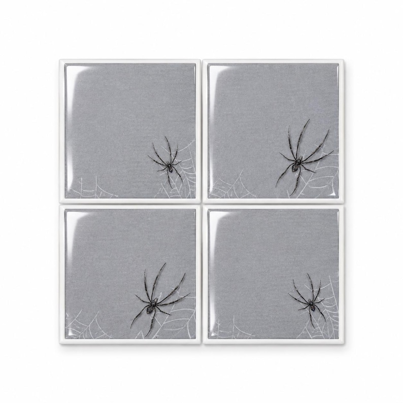 Peut inclure: Un ensemble de quatre dessous de verre carr&eacute;s avec un fond gris clair. Chaque dessous de verre pr&eacute;sente une illustration d'araign&eacute;e noire et un motif de toile d'araign&eacute;e blanche dans le coin. Finition brillante et bordure blanche.