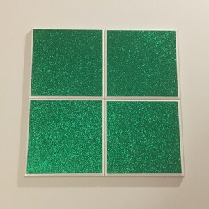 May include: Four square green glitter coasters with white borders.