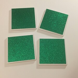 May include: Four square green glitter coasters with white borders.