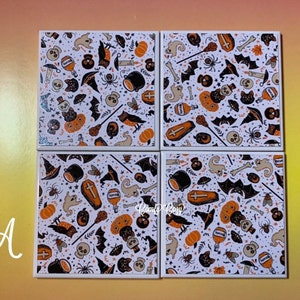 Pu&ograve; includere: Un set di quattro sottobicchieri quadrati con un motivo ripetuto di icone di Halloween, tra cui zucche arancioni, pipistrelli neri, teschi, fantasmi, calderoni, bare e cappelli da strega su uno sfondo bianco.