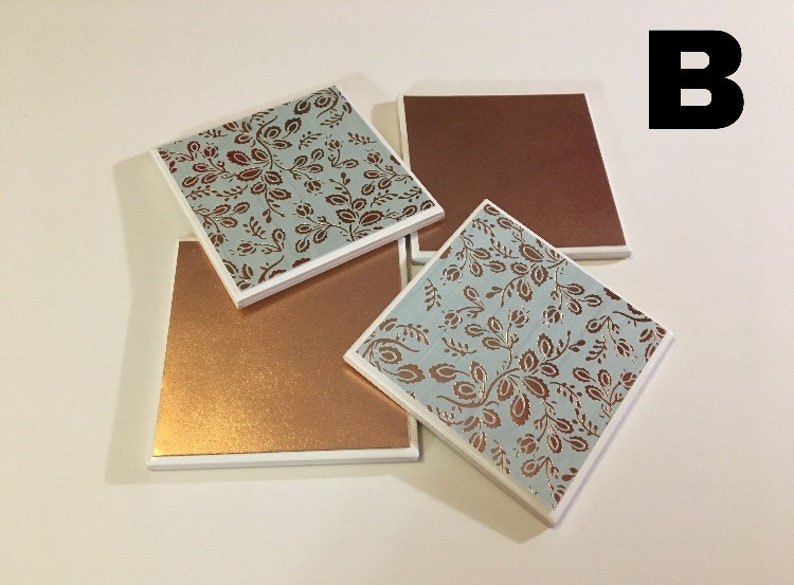 Puede incluir: Cuatro posavasos cuadrados con borde blanco. Dos posavasos presentan un patr&oacute;n floral azul y cobre. Dos posavasos son de cobre s&oacute;lido.