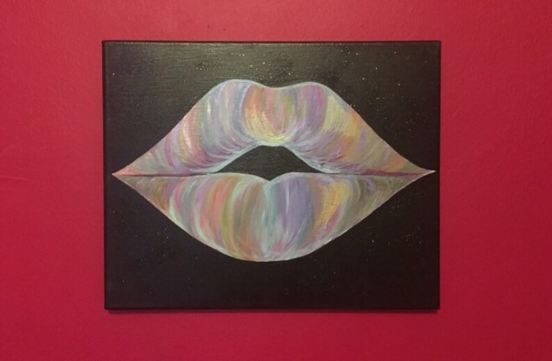 May include: A rectangular canvas painting featuring a pair of lips centered on a solid black background. The lips are rendered with blended brushstrokes of iridescent pastel colors including pink, purple, yellow, and blue, with a dark gap in the center.