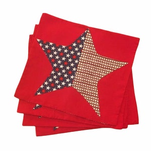 Peut inclure: Ensemble de quatre serviettes en tissu rouge avec un motif d'&eacute;toile bleu et blanc. L'&eacute;toile est faite d'un tissu &agrave; motifs avec des &eacute;toiles blanches sur un fond bleu et des rayures blanches et brunes.