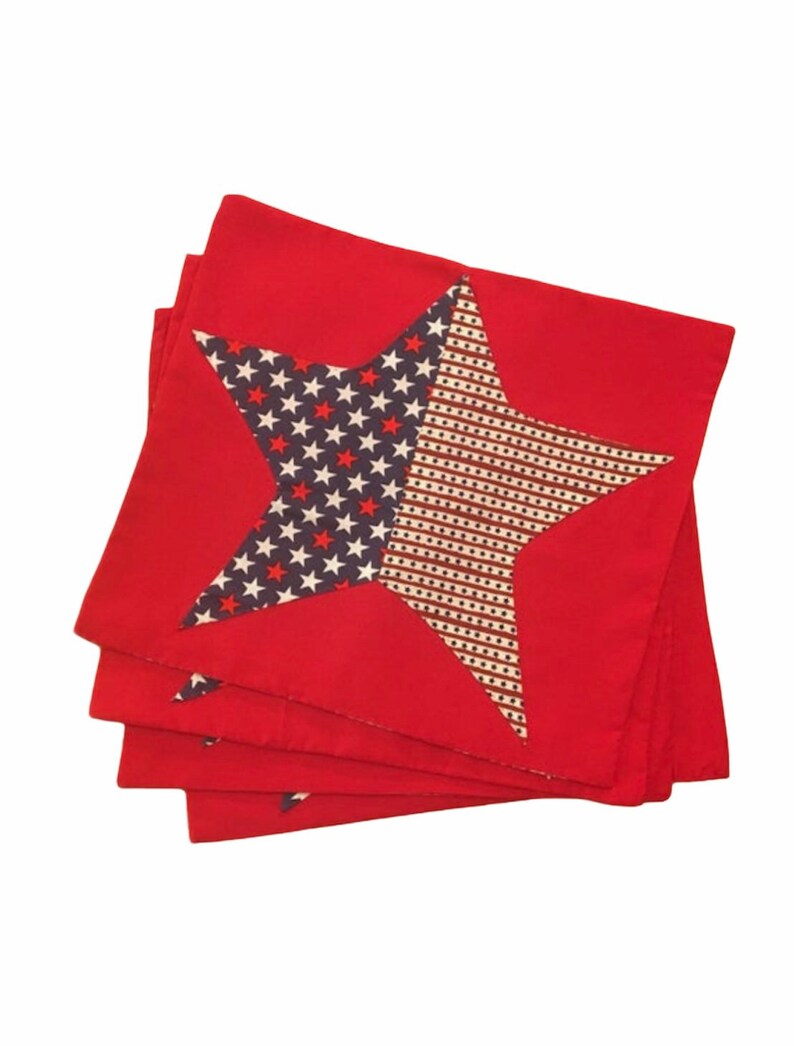 Peut inclure: Ensemble de quatre serviettes en tissu rouge avec un motif d'&eacute;toile bleu et blanc. L'&eacute;toile est faite d'un tissu &agrave; motifs avec des &eacute;toiles blanches sur un fond bleu et des rayures blanches et brunes.
