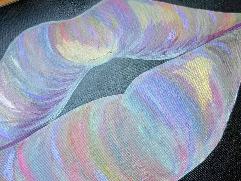 May include: A painting on a textured black canvas depicting a pair of lips rendered in iridescent brushstrokes of pastel pink, lavender, light blue, and soft yellow. The artwork features visible paint texture and a vibrant, multi-colored finish.