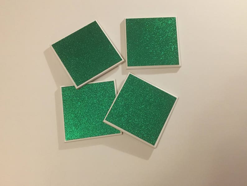 May include: Four square green glitter coasters with white borders.