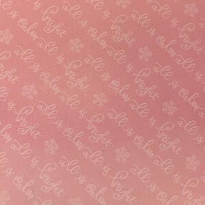 May include: A pink background with a repeating pattern of white text that says "all is calm all is bright". The text is in a cursive font and is surrounded by small snowflake designs.