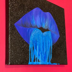 K&ouml;nnte beinhalten: Ein blauer Glitzer-Lippenabdruck auf einer schwarzen Glitzer-Leinwand. Der Lippenabdruck tropft mit blauem Glitzer.