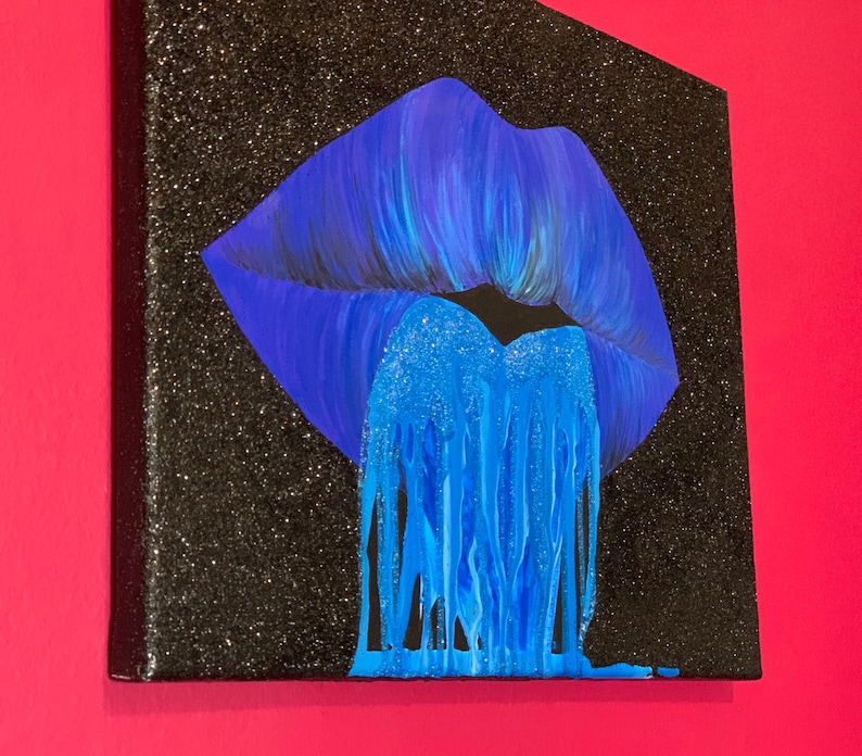 K&ouml;nnte beinhalten: Ein blauer Glitzer-Lippenabdruck auf einer schwarzen Glitzer-Leinwand. Der Lippenabdruck tropft mit blauem Glitzer.
